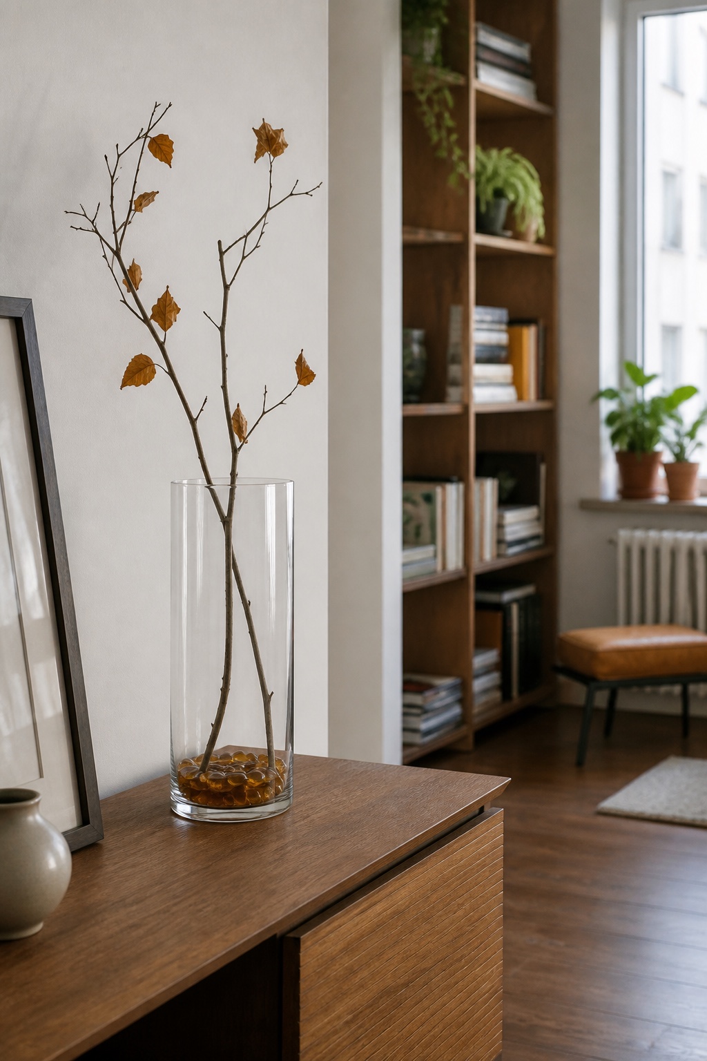 Bernsteinfarbene Glassteine als niedrige Basis unter zwei kahlen Zweigen in einer klaren Vase