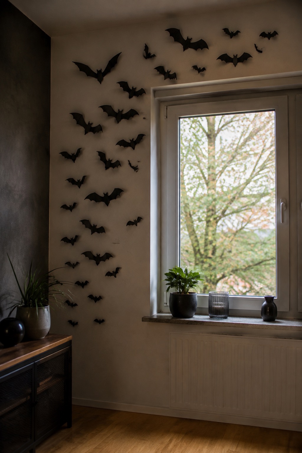 Schwarze Fledermäuse ziehen vom Fensterrahmen über die Wand eines Wohnzimmers