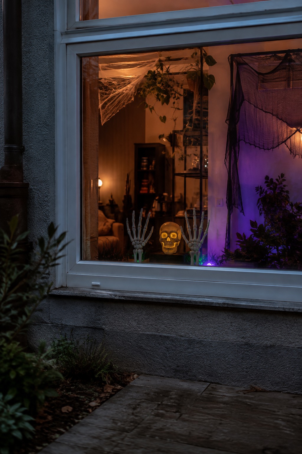 Zwei beleuchtete Skeletthände und ein Schädel tauchen hinter einer Fensterscheibe auf