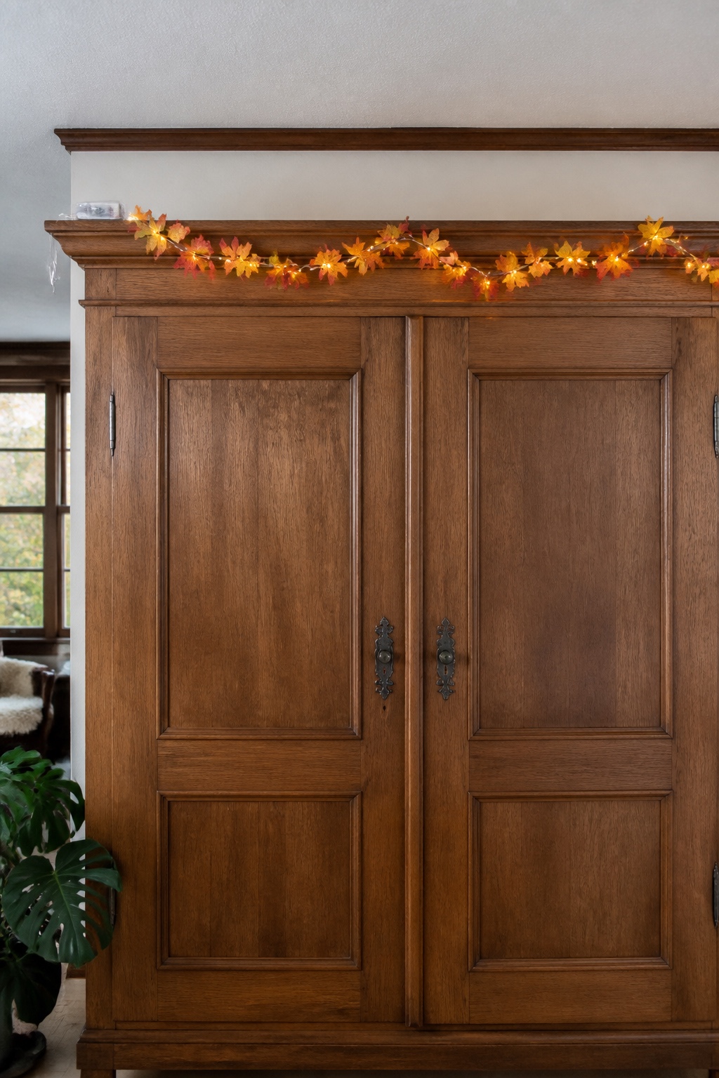 Leuchtende Herbstblättergirlande entlang der Oberkante eines alten Holzschranks