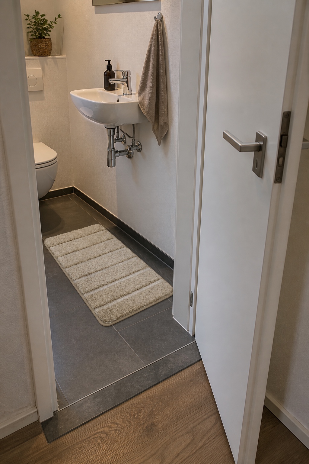 Kleine beige Badematte vor dem Waschbecken und außerhalb des Türschwenkbereichs im Gäste-WC