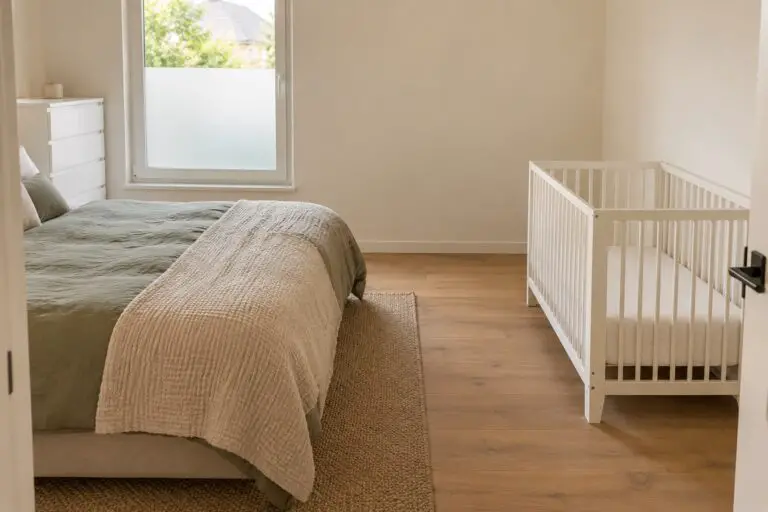 Kleines Elternschlafzimmer mit getrenntem leeren Babybett und freiem Durchgang